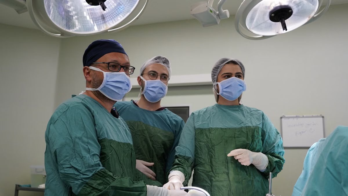 Surgeons focused in an operating room, wearing sterile attire, preparing for surgery.